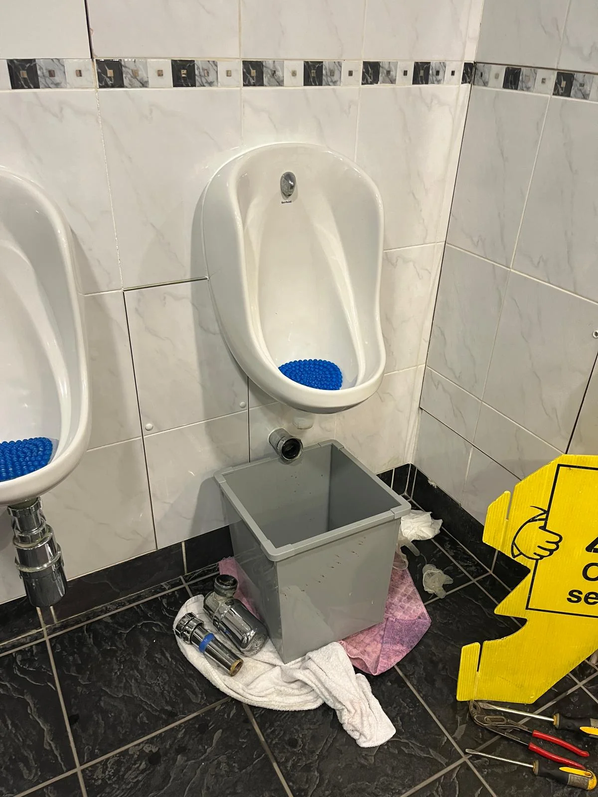 Commercial urinal inspected before plumbing repair