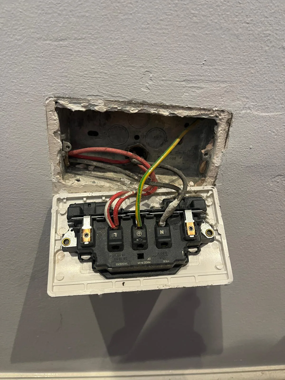 Electrician checking wiring during double socket replacement